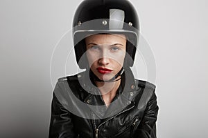 Closeup portrait of biker woman over white background, wearing stylish black sportive helmet and leather jacket.