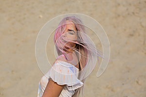 Closeup portrait of blonde girl posing covered with dry Holi paint at the desert