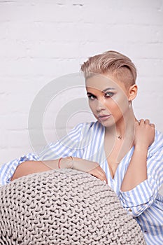 Closeup portrait blonde model with bright make-up and short hair with shaved temples in a modern silver jewelry, earrings,
