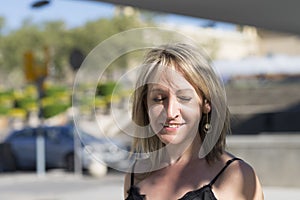Closeup portrait of a blonde woman eyes closed while smiling outdoors