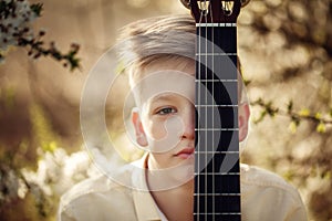 Closeup Portrait boy with guitar in summer day.