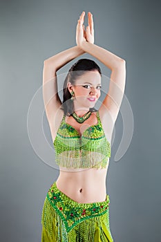 Closeup portrait of brunette girl in green belly dancer costume poses for photo