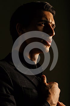 Closeup portrait of a business man dressed in black suit portrait against a dark background