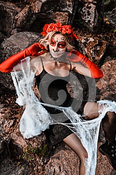 Closeup portrait of Calavera Catrina. Young woman with sugar skull makeup and white spiderweb. Dia de los muertos. Day