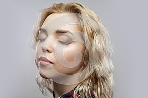 Closeup portrait of calm beautiful blonde young woman in casual red checkered shirt standing with closed eyes and relaxed face