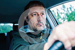 Closeup portrait of cautious male driver gripping the steering wheel and driving a car on a road trip