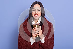 Closeup portrait of charismatic beautiful woman smiling sincerely, having red lips, holding thermo mug with hot drink in both