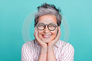 Closeup portrait of charming senior pensioner woman looking dreamy hold hands on cheeks isolated teal color background