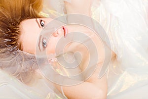 Closeup portrait of charming young blond woman beautiful girl is in shining water looking at the camera