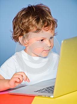 Closeup portrait of clever child boy pupil with laptop. Child from elementary school. Cheerful smiling child use laptop