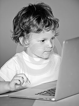 Closeup portrait of clever child boy pupil with laptop. Child from elementary school. Cheerful smiling child use laptop