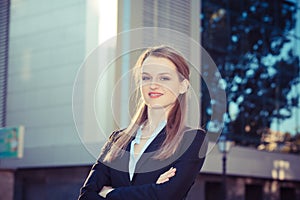 Closeup portrait of a confident blonde businesswoman standing in the city next to office building outdoors