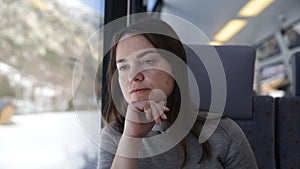 Closeup portrait of contemplative brunette woman travelling by express train, sitting on soft comfortable seat and