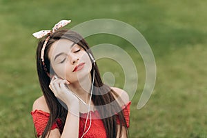 Closeup portrait of content young beautiful woman wearing headphones, listening to music with her eyes closed and lying