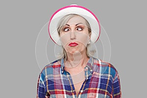 Closeup portrait of crazy crosseyed stylish mature woman in casual style with white hat standing, crossed eyes and looking with