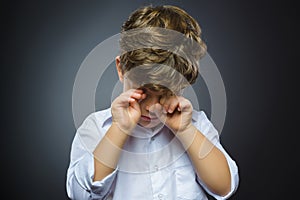 Closeup Portrait of crying boy with astonished expression while standing against grey background