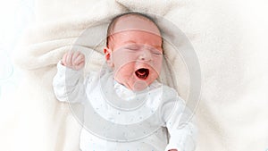 Closeup portrait of crying newborn baby lying in baby crib