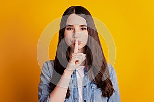Closeup portrait of cunning woman fingr cover lips  yellow wall background