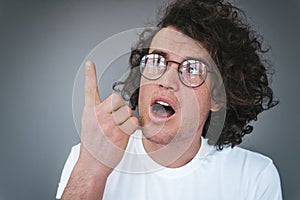 Closeup portrait of curly hair amazed handsome man has excited expression, look up indicate finger up to advertisement information