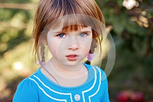 Closeup portrait of cute adorable little red-haired Caucasian girl child with blue eyes