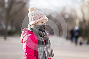 Closeup portrait of cute baby girl wearing knitted hat and winter jacket outdoors