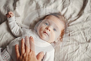 Closeup portrait of cute Caucasian newborn baby. Adorable funny child infant with blue grey eyes and red hair lying on a bed