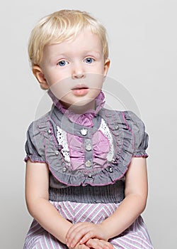 Closeup portrait of cute child toddler girl with blonde hair and blue eyes in vintage retro victorian gothic dress posing sitting