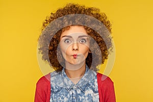 Closeup portrait of cute funny woman with fluffy curly hair expressing amazement with fish face grimace