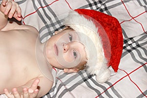 Closeup portrait of a cute little baby boy wearing red Santa Claus traditional Christmas costume.Christmas of infant in red cap. N