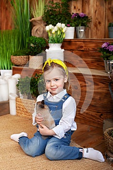 Closeup portrait of cute little girl and brown rabbit at home. Child plays with a rabbit in backyard. Easter. Concept child and an