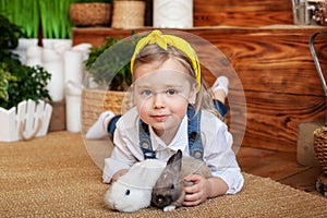 Closeup portrait of cute little girl and white and brown rabbits. Child playing with rabbits. Easter celebration. Concept child an