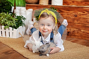 Closeup portrait of cute little girl and white and brown rabbits. Child playing with rabbits. Easter celebration. Concept child an