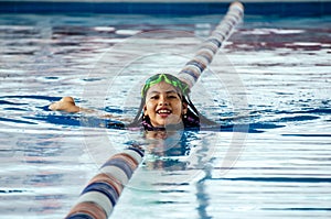 Closeup portrait of cute little peruvian girl swimming in the pool, happy child having fun in water.