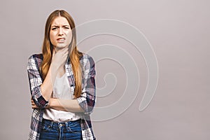 Closeup portrait of cute sick young blonde woman in casual having sore throat, holding hand on her neck/Throat pain, painful