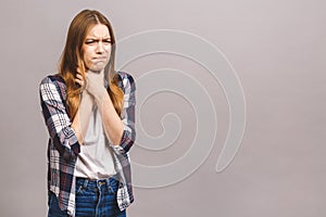 Closeup portrait of cute sick young blonde woman in casual having sore throat, holding hand on her neck/Throat pain, painful