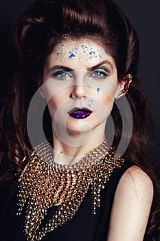 Closeup portrait with deep blue eye, creative makeup and golden accessories