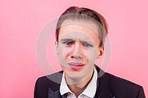 Closeup portrait of desperate man in suit crying and looking at camera with grimace of pain , insulted, deeply offended, resentful