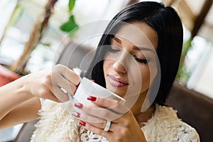 Closeup portrait of drinking coffee or tea beautiful brunette girl young woman having fun gently smiling eyes closed