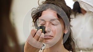 Closeup portrait of elegant female client being given makeup and hairstyle in four hands in beauty studio. Close up of