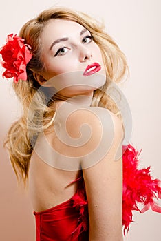 Closeup portrait of elegant romantic blond woman with green eyes in red dress with rose in the hair