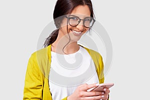 Closeup portrait of European beautiful young woman smiling and looking to the camera during using cellphone for messaging to her