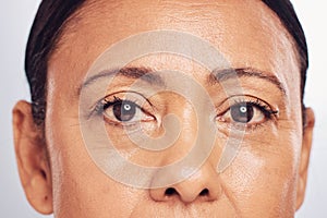 Closeup, portrait and eyes of a mature woman isolated on a studio background for skincare beauty. Wrinkles, treatment