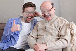 Closeup portrait, family, young man holding older manshowing thumb up