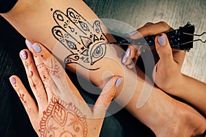 Artist applying henna mehndi tattoo on female hand