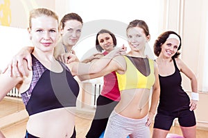 Closeup Portrait of Five Happy Caucasian Female Athletes Posing Together Embraced Against Fitballs in Gym