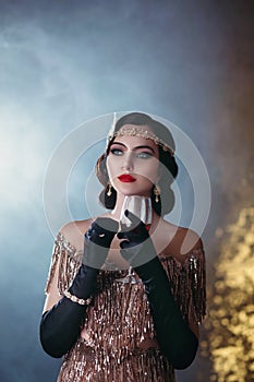 Closeup portrait flapper woman with glass of red wine. golden headband, finger wave hairstyle, vintage style 20s dress