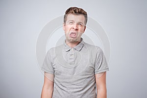 Closeup portrait of funny angry young bully man sticking his tongue out at you camera gesture