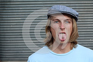 Closeup portrait, funny annoyed young childish rude bully man sticking his tongue out at you camera, on gray background.