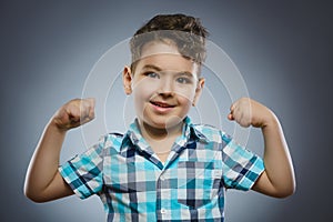 Closeup Portrait of Funny child. Strong kid showing his hand biceps muscles