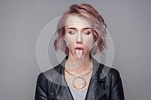 Closeup portrait of funny closed eyes beautiful girl with short hairstyle and makeup in casual style black leather jacket standing